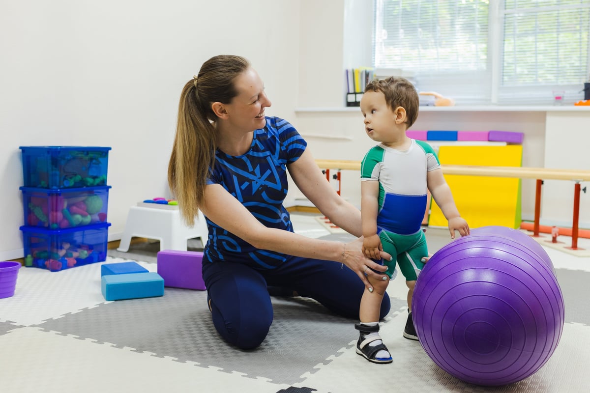 Therapist supporting a patient through a standing balance rehabilitation exercise
