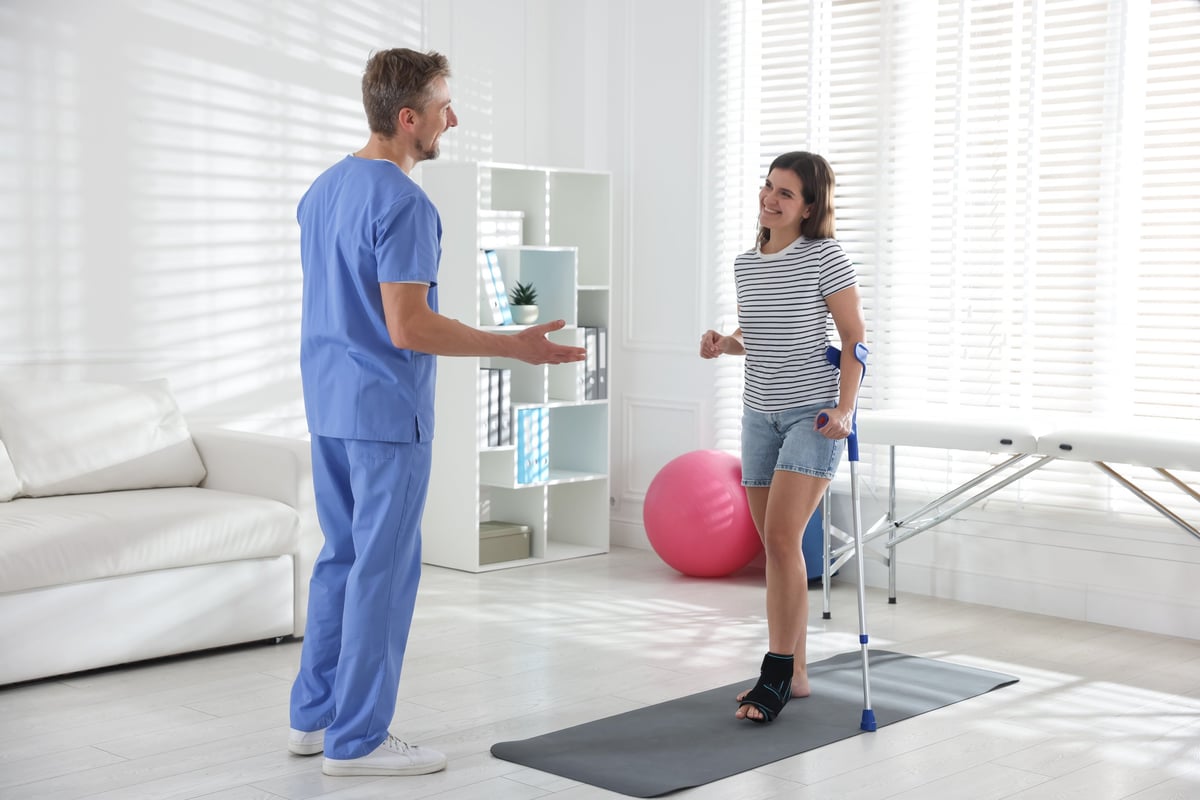 Physiotherapist assisting a patient using crutches after surgery
